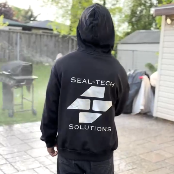 Team member wearing a Seal-Tech Solutions hoodie on a finished backyard patio